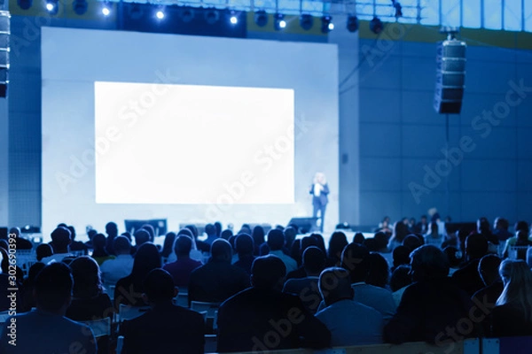 Fototapeta Speaker Giving a Talk at Business Meeting. Audience in the conference hall. blue tinted photo Focus on unrecognizable people
