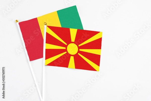 Fototapeta Macedonia and Guinea stick flags on white background. High quality fabric, miniature national flag. Peaceful global concept.White floor for copy space.