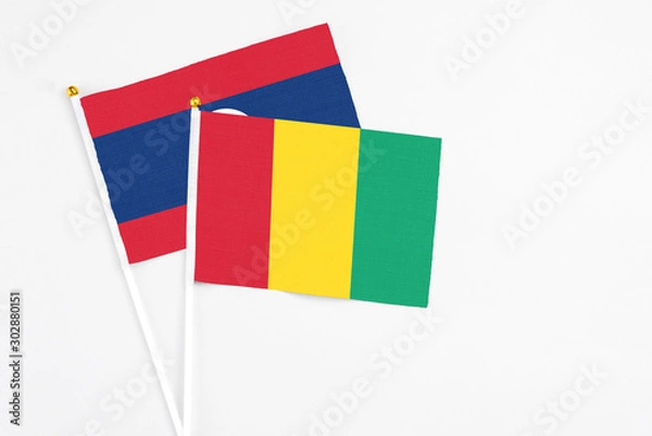 Fototapeta Guinea and Laos stick flags on white background. High quality fabric, miniature national flag. Peaceful global concept.White floor for copy space.