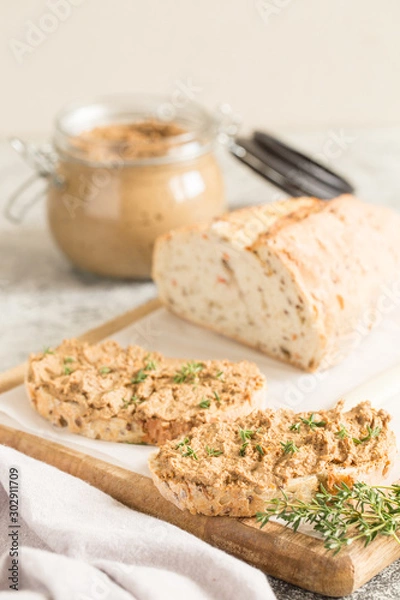 Fototapeta Fresh homemade chicken liver pate. Chicken liver pate on bread and in jar on a light background