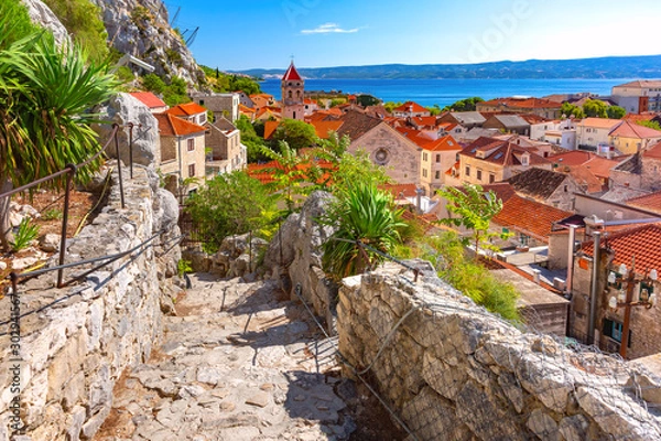 Obraz Sunny red roofs, Old city street with stone stairs and Church of St Michael in town and port Omis, popular tourist spot in Croatia