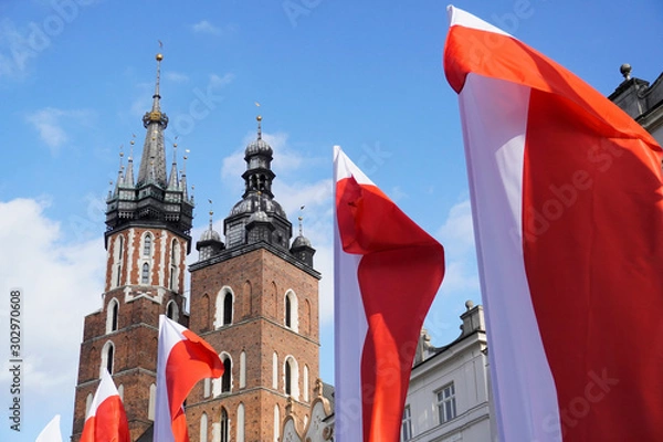 Fototapeta Polish red and white flags in the Old town in front of the building on a Sunny day.May 1, November 11, flag, independence or labor Day. Public holiday in Poland. decoration of the city with flags.