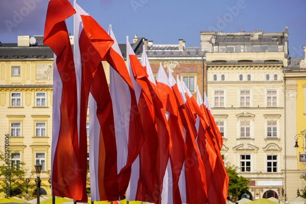 Obraz Polish red and white flags in the Old town in front of the building on a Sunny day.May 1, November 11, flag, independence or labor Day. Public holiday in Poland. decoration of the city with flags.