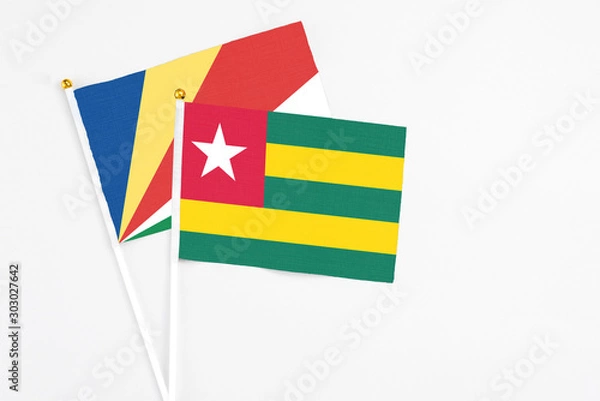 Fototapeta Togo and Seychelles stick flags on white background. High quality fabric, miniature national flag. Peaceful global concept.White floor for copy space.v