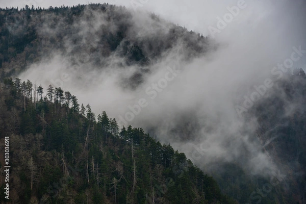 Fototapeta Thick Cloud Breaks Passes Between Two Ridges