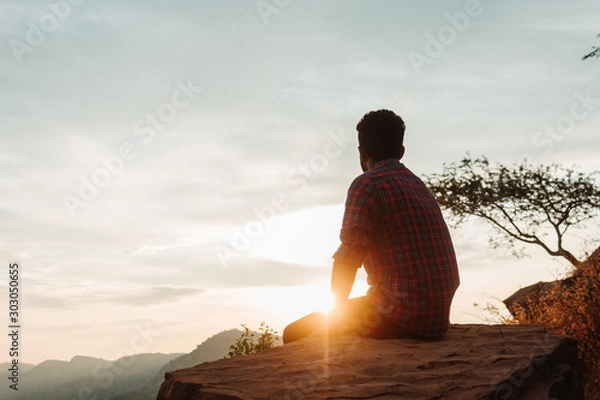 Fototapeta Indian male model sitting in front of the sunset at Kalo Dungar in Kutch, Gujarat, India