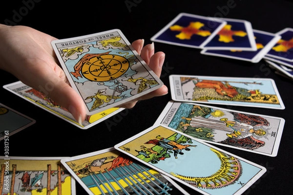 Fototapeta Bangkok,Thailand,november.13.19. Tarot cartomancy. Cards for divination on a black background with the reflection of the moon. Divination for Christmas. Fortune-telling and the future.