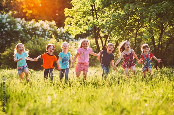 Fototapeta Large group of kids, friends boys and girls running in the park on sunny summer day in casual clothes .