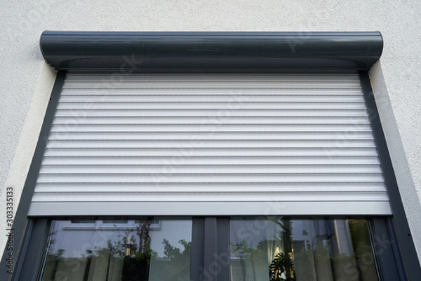 Obraz Light roller shutter curtains mounted on a dark window