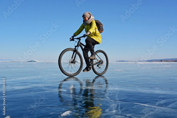 Obraz Ice biker traveler with backpacks on bike on ice of Lake Baikal. Winter sport concept. Cycling.