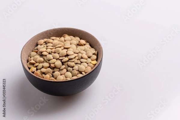 Fototapeta Dry uncooked lentils isolated on white background, copy space, studio shot, soft light. Christmas and New Year dish