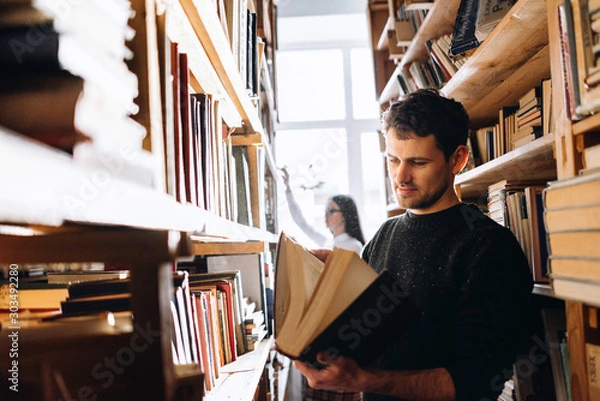 Obraz people, knowledge, education and school concept - happy student girl and the guy choose books in the old library