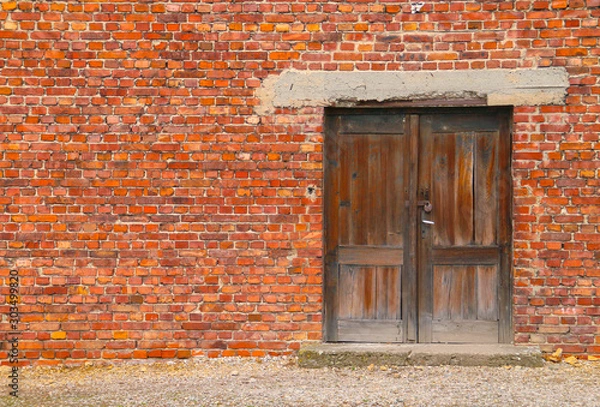 Fototapeta Una vieja puerta de madera en una pared de ladrillos.