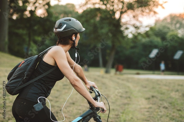 Fototapeta Healthy sporty woman riding her bicycle at park. Portrait woman riding mountain bike in countryside
