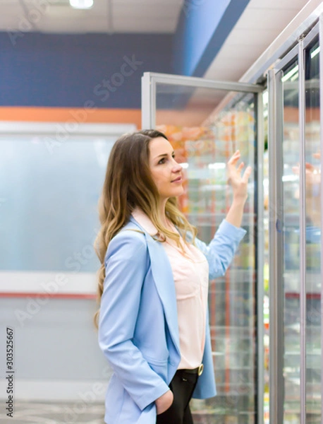 Fototapeta Woman choosing a dairy products at supermarket. Reading product information