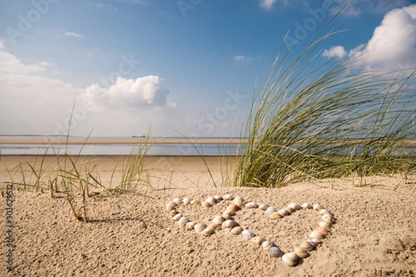 Obraz Wonderful dune beach on the North Sea island Langeoog in Germany with sky, clouds, sand, hearts made of sea shells and grass on a beautiful summer day