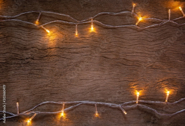 Fototapeta Christmas lights on wooden plank background. Merry Christmas and happy new year with copy space for a text...