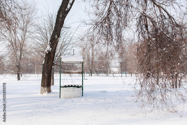 Fototapeta Winter. An old water well is covered in snow.