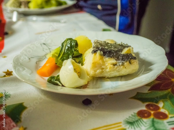 Fototapeta codfish with mashed potatos, spinach and eggs on white plate. Traditional portuguese crhistmas night food
