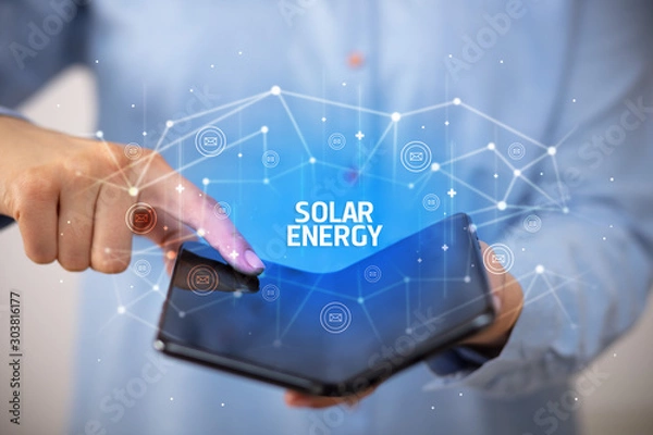 Obraz Businessman holding a foldable smartphone with SOLAR ENERGY inscription, new technology concept
