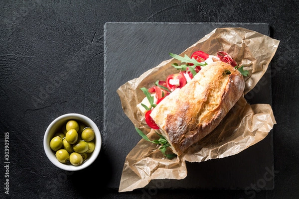 Fototapeta Sandwich with jamon, cheese, tomatoes and arugula on a black background