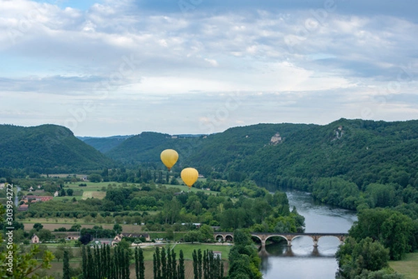 Fototapeta Two yellow hot air ballons flying over the Dordogne river with chateau castlenaud in the background Dordogne France