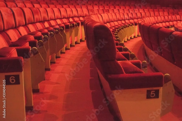 Fototapeta Rows of red cinema seats with number. View of empty theater hall. Comfort chairs in the modern theater interior