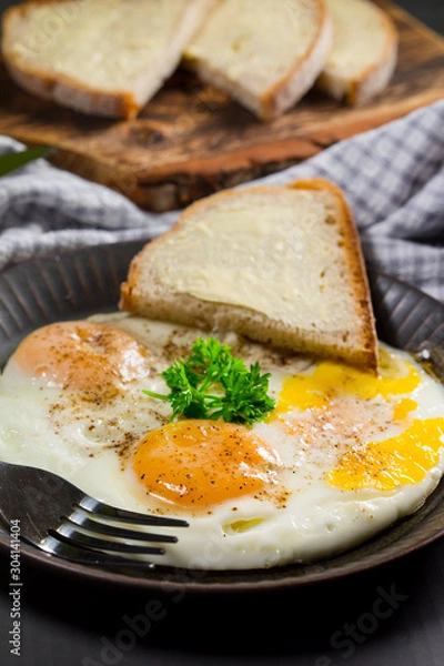 Fototapeta Fried eggs and bread for breakfast on a gray background.