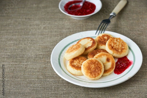 Fototapeta Cottage cheese pancakes with raspberry jam on a white plate 