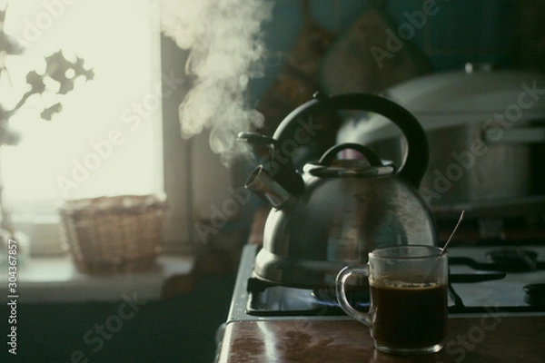 Obraz  Kitchen. A metal kettle boils on the stove. A cup of coffee. Window. Brown set.