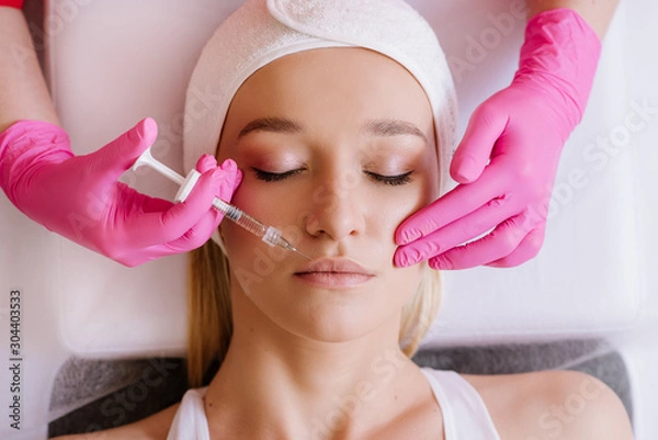 Fototapeta Contour plasticity of lips, augmentation of lips, introduction of filler of hyaluronic acid on woman in SPA center
