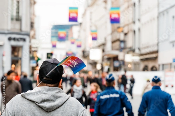 Fototapeta Brusseles, Belgium - May 2019: Symbol of the LGBT parade "Belgium pride" paper flag sticking out of a passer‚Äôs cap. View from the back