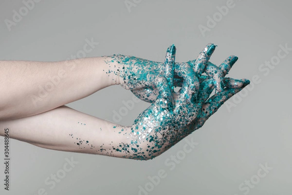 Fototapeta Beautiful woman hands with blue glitter in front of black, can be used as background