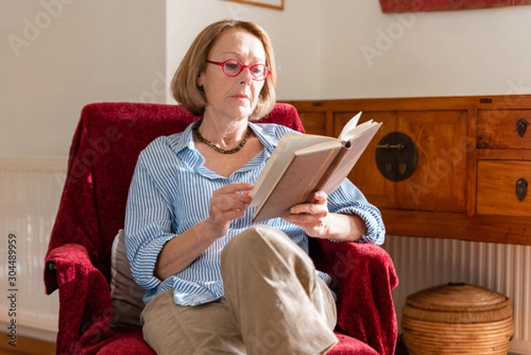 Obraz Elegant mature woman is reading a book at home