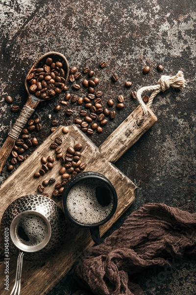 Fototapeta Coffee on wooden board with coffee beans on dark textured background. Top view with copy space. Background with free text space.