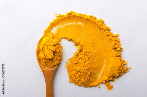 Obraz Closeup of wooden spoon and turmeric on the white table.Top view of turmeric condiment