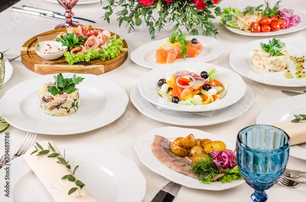 Obraz Served for holiday banquet restaurant table with dishes, snack, salads, cutlery, wine and water glasses. European food in a restaurant setting. Table set for an event party. catering