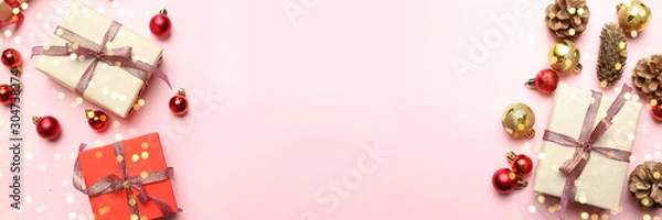 Fototapeta Merry Christmas and New Year congratulation background with beautiful gifts boxes, golden shiny ribbons and red balls on pink background.