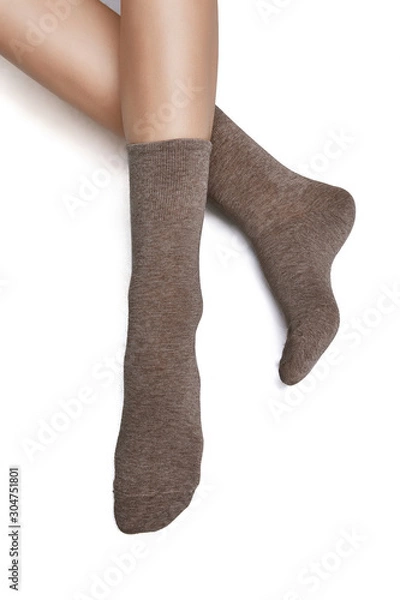 Fototapeta Cropped shot of a girl's foots, lying on a white background. It is grey socks on her foots. 