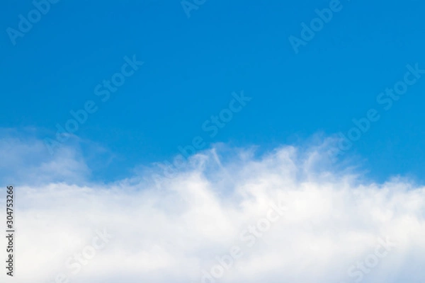 Fototapeta The sky is bright and the clouds are arranged in a long line below like waves. During the daytime.