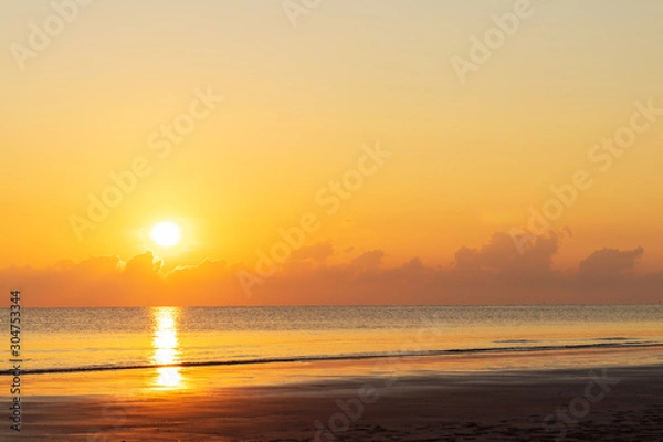 Fototapeta Sunset at sea There is reflection on the water and the beach. Waves hit the coast.