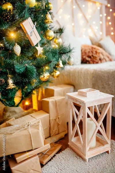 Fototapeta Christmas interior of the living room - a bright room with New Year's decoration - Christmas trees, gift boxes, a fireplace with candles, decorated with a pine garland with toys. New year interior
