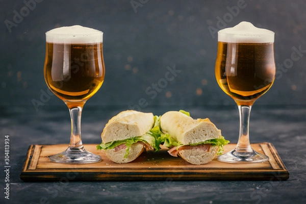 Fototapeta Two glasses of beer with foam and delicious sandwiches in a pub.