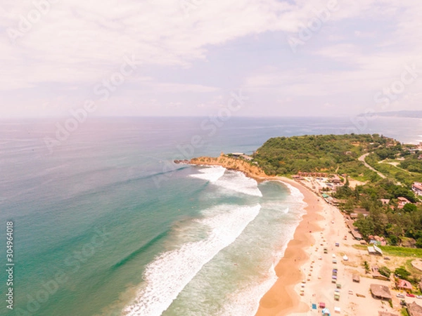 Fototapeta Aerial Coastline cliffs. Beach ocean drone view. Dramatic aerial DRONE view of Montanita beach town, and 'The Point' cliffs at sunrise. View of the ocean, sand, coastline, waves and rocks. Ecuador.