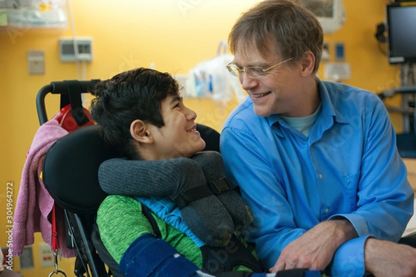 Obraz Father talking with disabled son in wheelchair at hopsital room