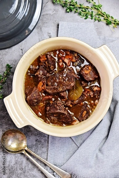 Fototapeta Beef bourguignon in the pot on the grey background, top view
