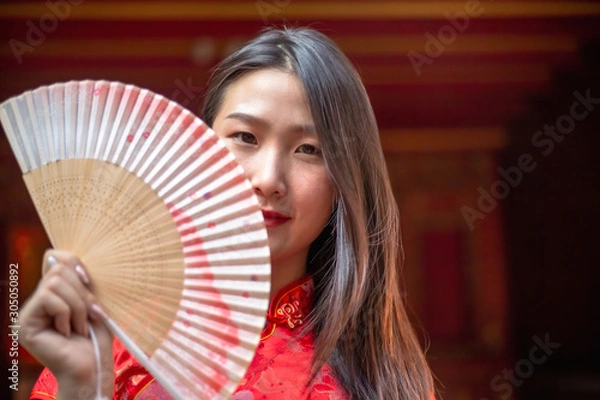 Fototapeta Beautiful young Chinese woman in a Cheongsam dresses or Chinese traditional dresses standing in Chinese Temple.