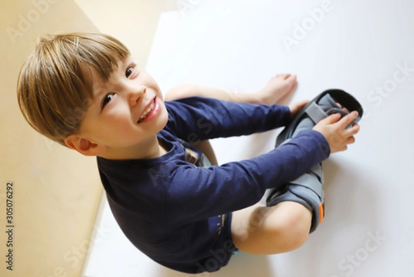 Obraz Ein dreijähriger Junge trägt eine Fußorthese