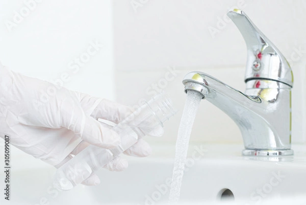 Fototapeta Tap water analysis quality control concept. Hand with a flask and water tap ckose up.
