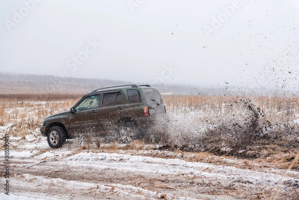 Fototapeta off-road driving. in a jeep on the first snow. car in the mud. driving through the mud in a simple car.